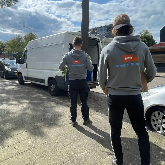 Verhuizers lopen naar verhuisbus tijdens professionele verhuizing in woonwijk