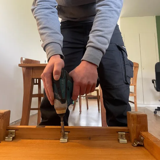 Verhuizer demonteert meubel met schroefmachine tijdens professionele verhuizing